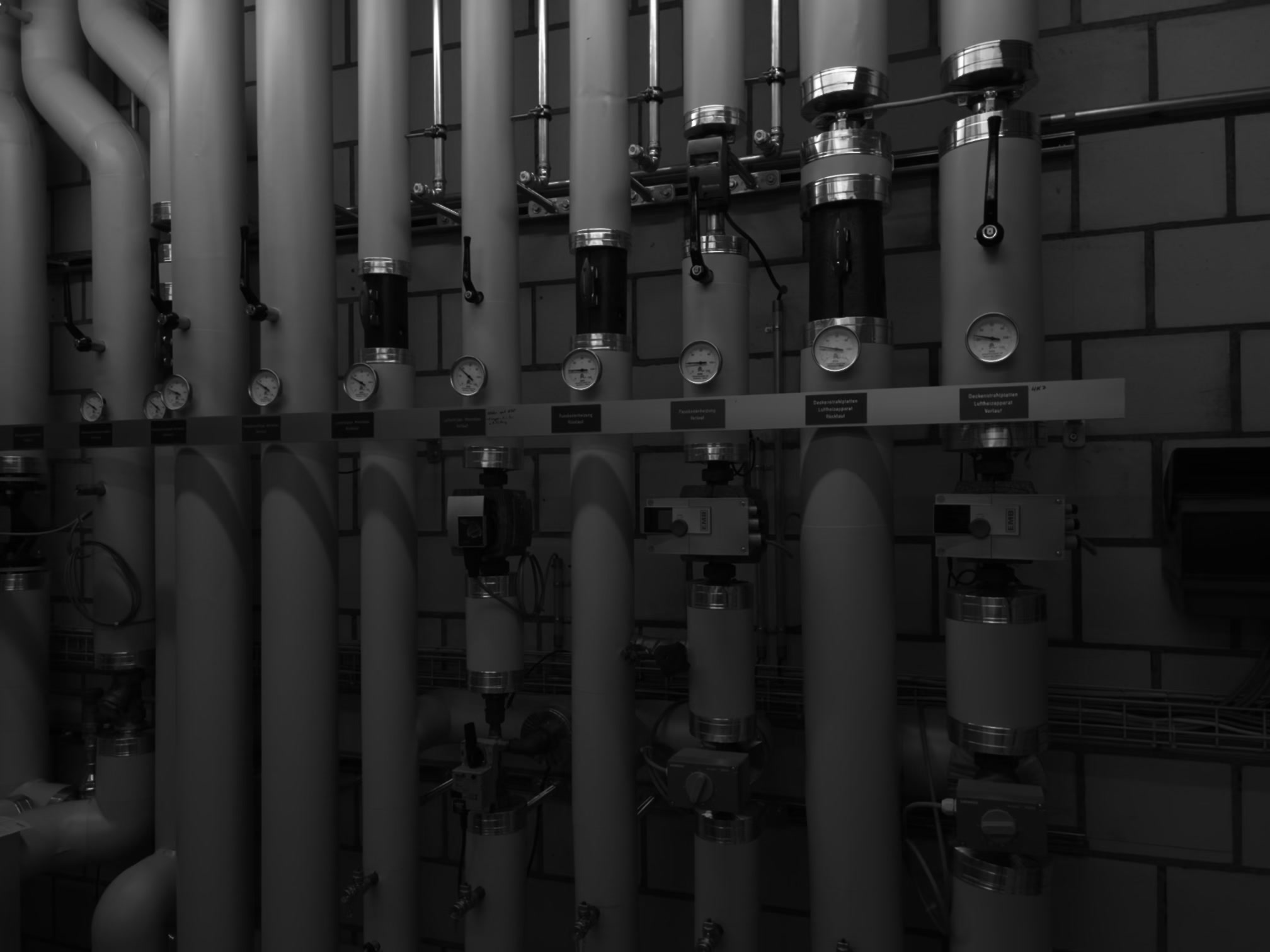 Rohrleitungssystem mit Regelarmaturen – Detailansicht der Heizungsverteilung mit beschrifteten Steigleitungen, Manometern und Stellantrieben. Übersichtliche und wartungsfreundliche Ausführung.